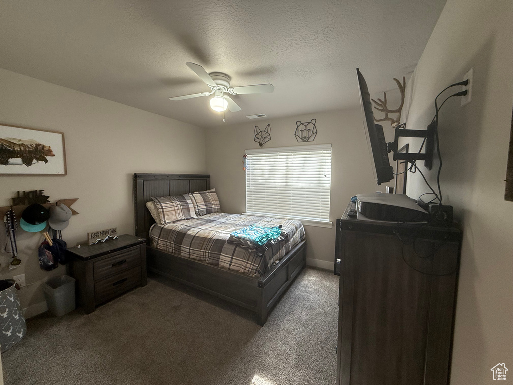 Bedroom with a ceiling fan, a textured ceiling, light colored carpet, and baseboards