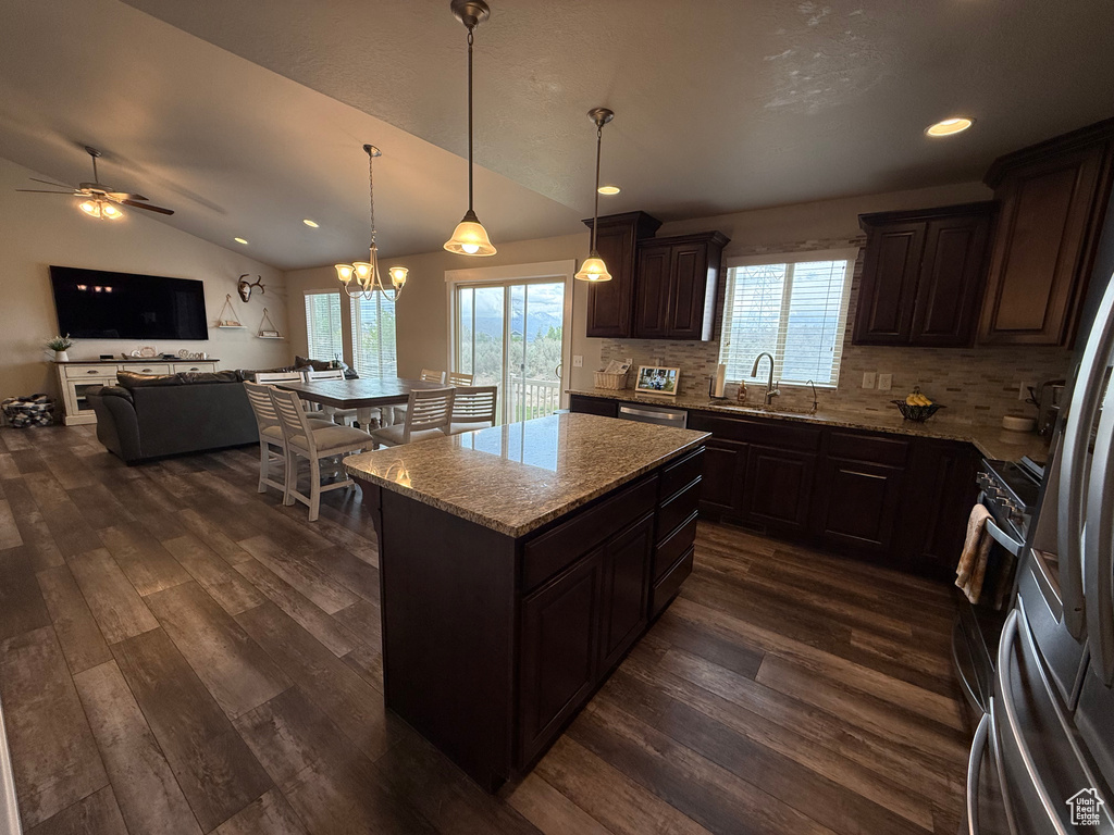 Kitchen with dark wood finished floors, decorative backsplash, a sink, a ceiling fan, and light stone countertops
