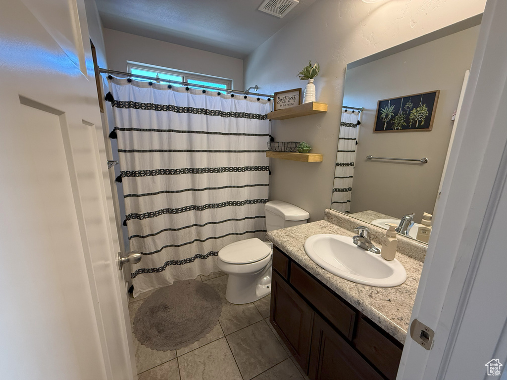 Bathroom featuring tile patterned floors, vanity, a shower with curtain, toilet, and visible vents