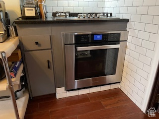 Details with dark wood finished floors, appliances with stainless steel finishes, and dark countertops
