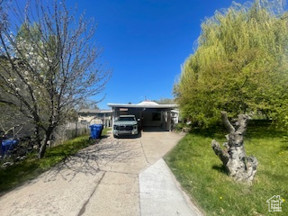 View of front of home featuring driveway, a front yard, and an attached carport
