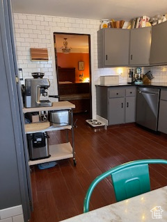 Kitchen featuring dishwasher, backsplash, dark wood-style flooring, and gray cabinetry