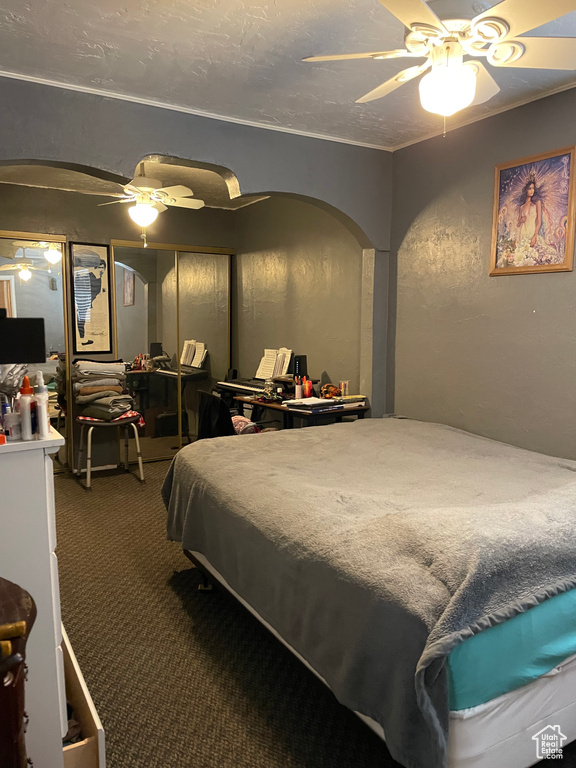 Carpeted bedroom featuring arched walkways and ceiling fan
