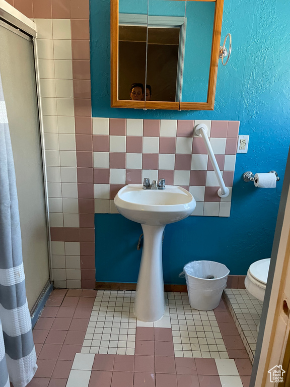 Bathroom with a shower stall, toilet, and tile patterned flooring