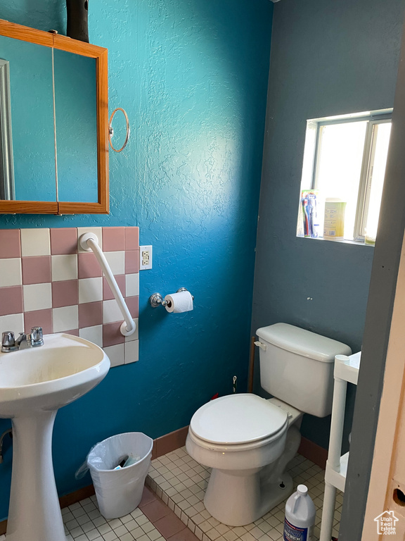 Half bath featuring tile patterned floors, baseboards, toilet, and a sink