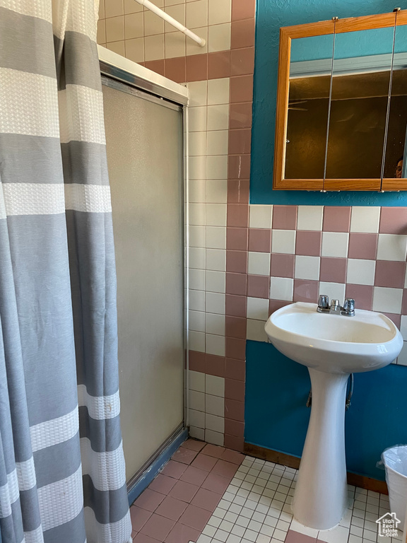 Full bathroom with a stall shower, tile walls, and tile patterned floors