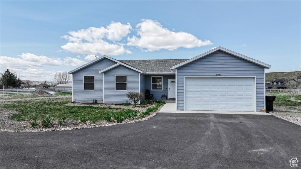 Ranch-style home with an attached garage, driveway, and fence