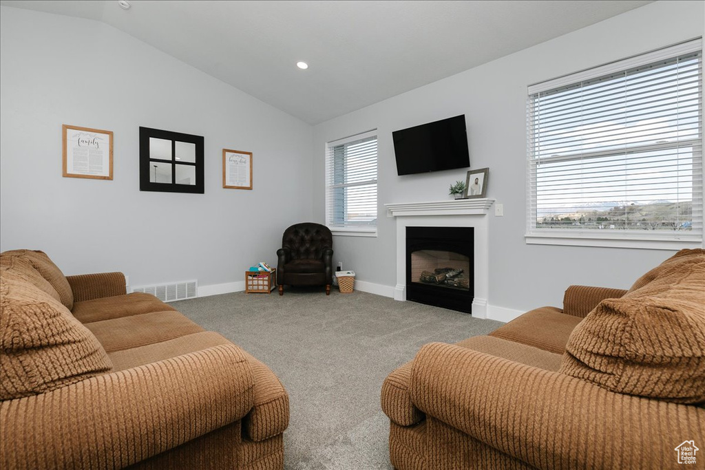 Carpeted living area featuring recessed lighting, lofted ceiling, visible vents, baseboards, and a fireplace