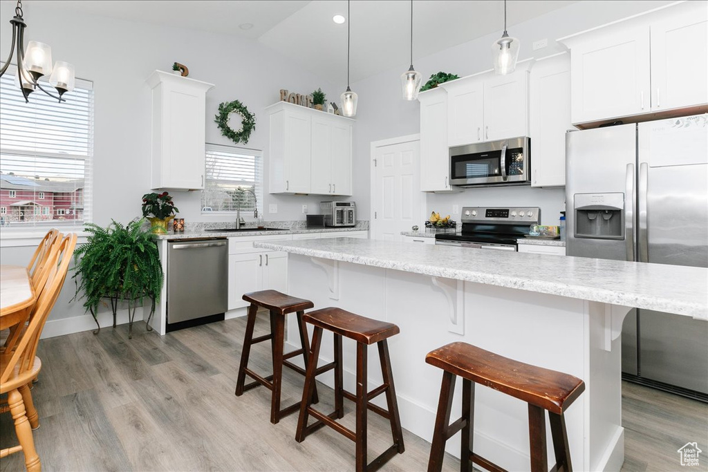 Kitchen with light wood-style floors, white cabinetry, stainless steel appliances, and a sink