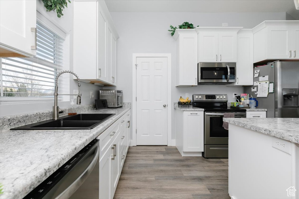 Kitchen with stainless steel appliances, a sink, and white cabinetry