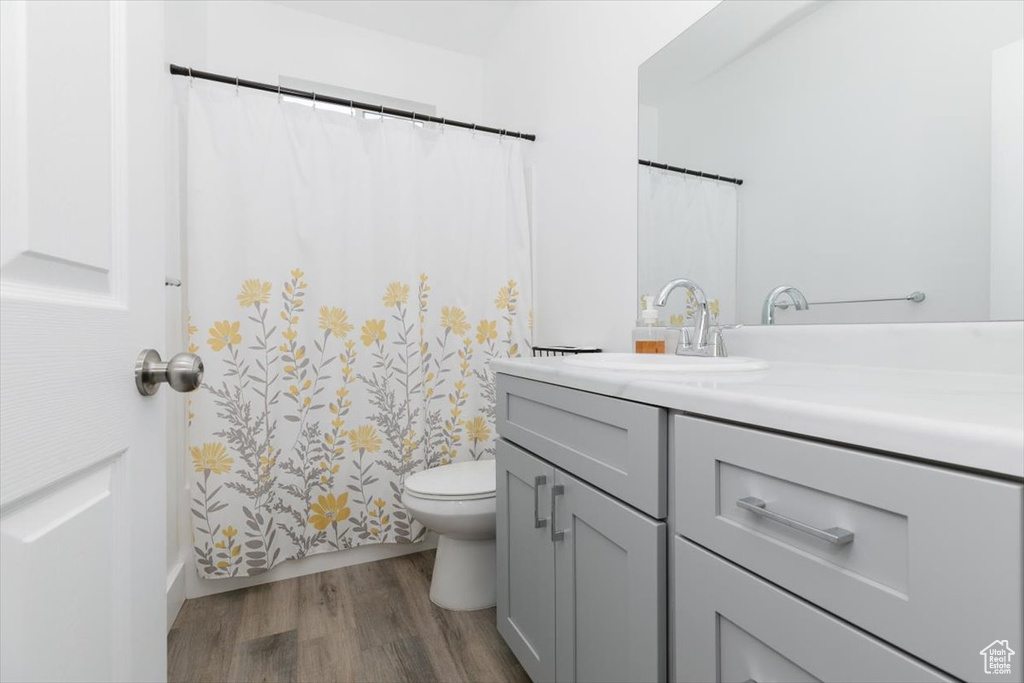Full bath with toilet, vanity, and wood finished floors