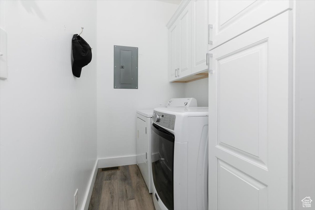 Washroom featuring electric panel, baseboards, wood finished floors, independent washer and dryer, and cabinet space