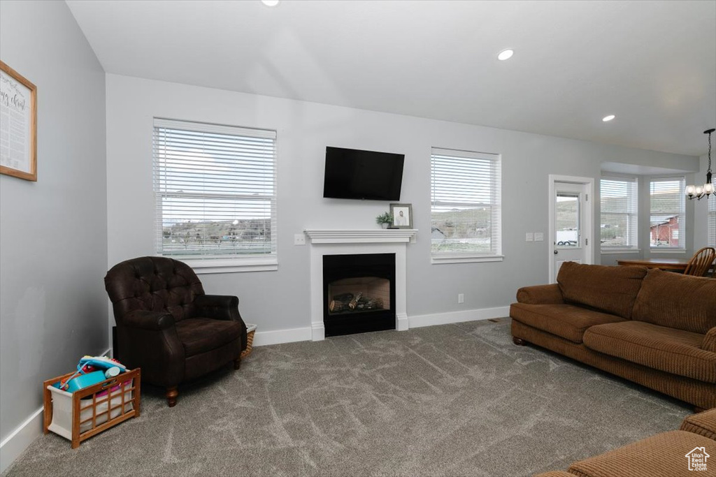 Living room with baseboards, a fireplace, a chandelier, and carpet flooring