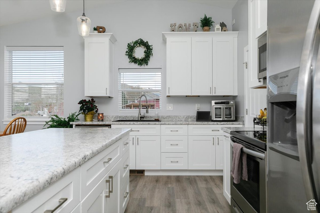 Kitchen with vaulted ceiling, light wood-type flooring, stainless steel appliances, and a sink