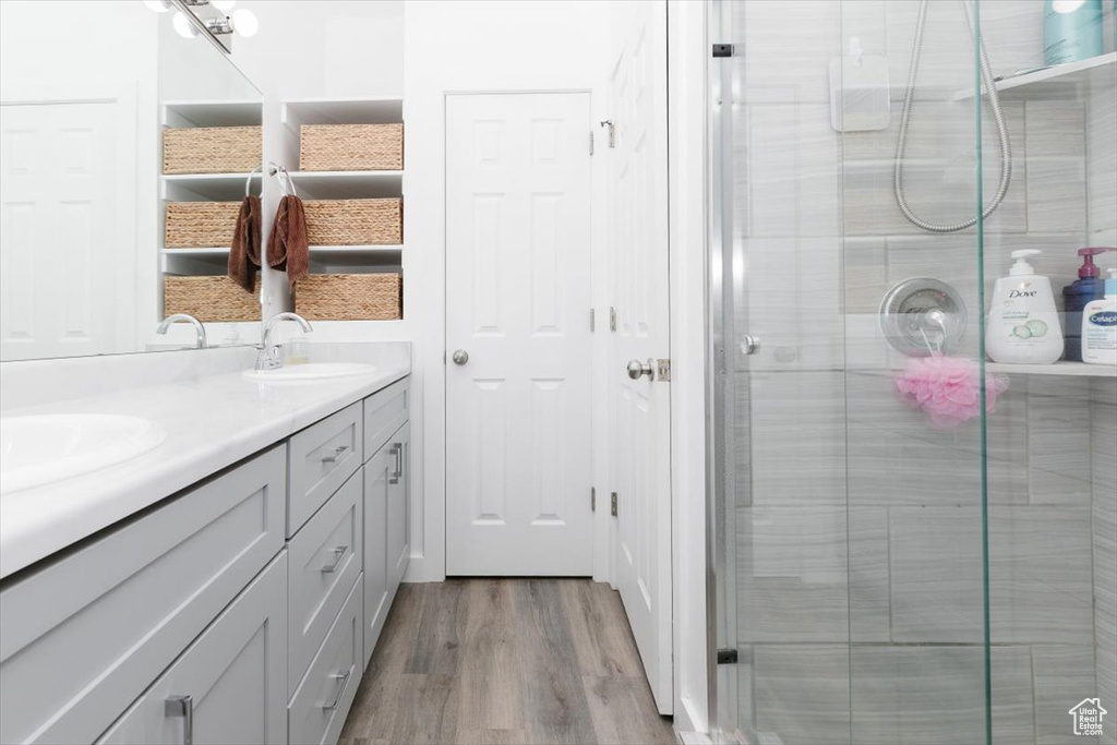 Full bathroom with wood finished floors, a sink, double vanity, and a stall shower