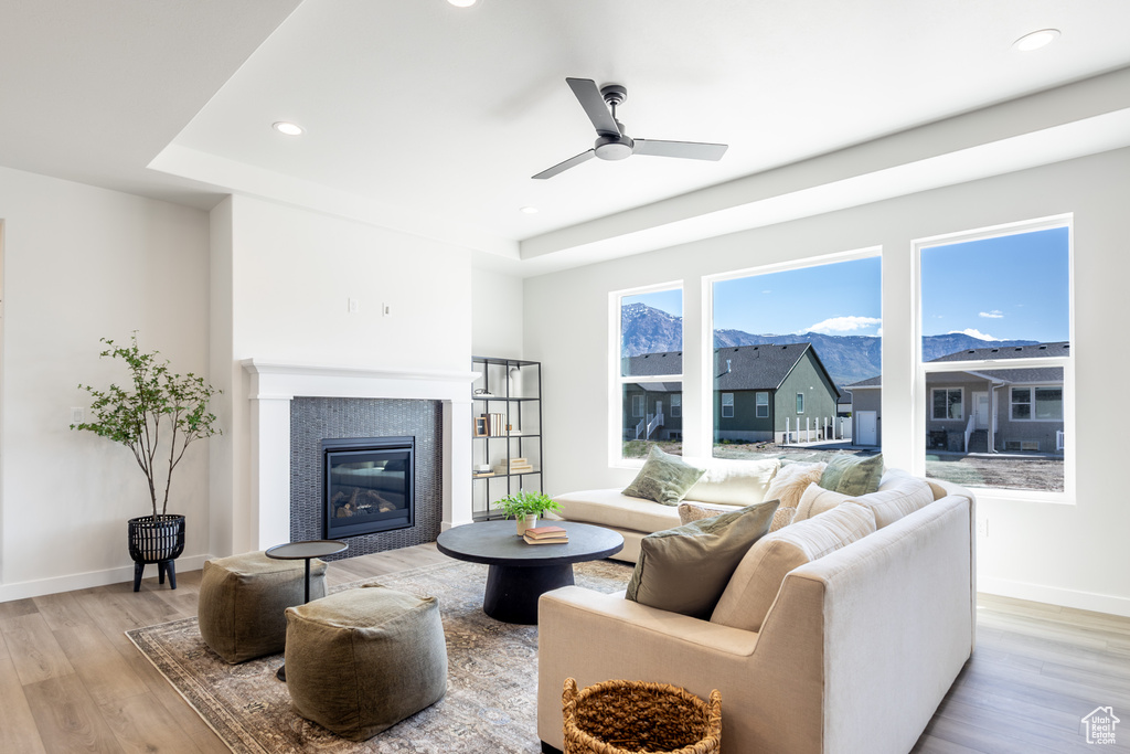 Living area featuring light wood-style flooring, a tile fireplace, baseboards, recessed lighting, and a ceiling fan