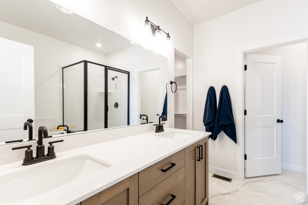 Bathroom with a shower stall, double vanity, marble finish floors, and baseboards