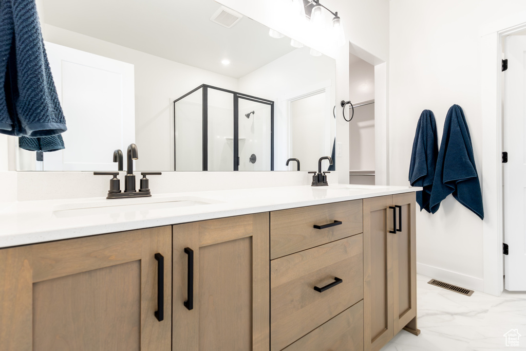 Bathroom featuring double vanity, a stall shower, and marble finish flooring