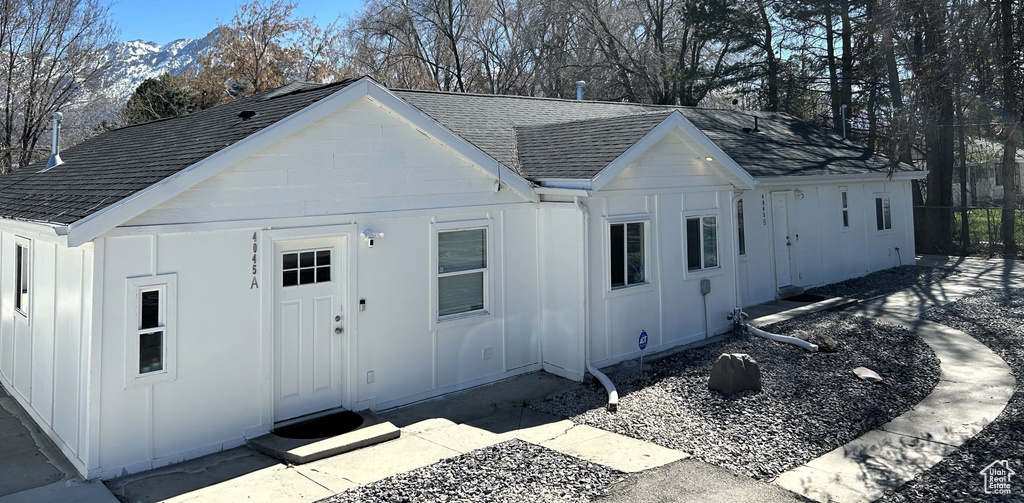 View of front of property with roof with shingles, board and batten siding, and fence