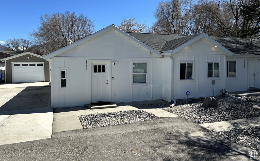 Ranch-style house with board and batten siding, an outbuilding, roof with shingles, driveway, and a garage