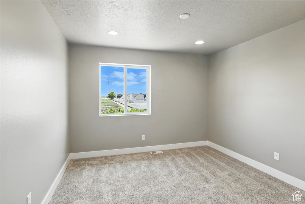 Empty room with light colored carpet, a textured ceiling, and recessed lighting