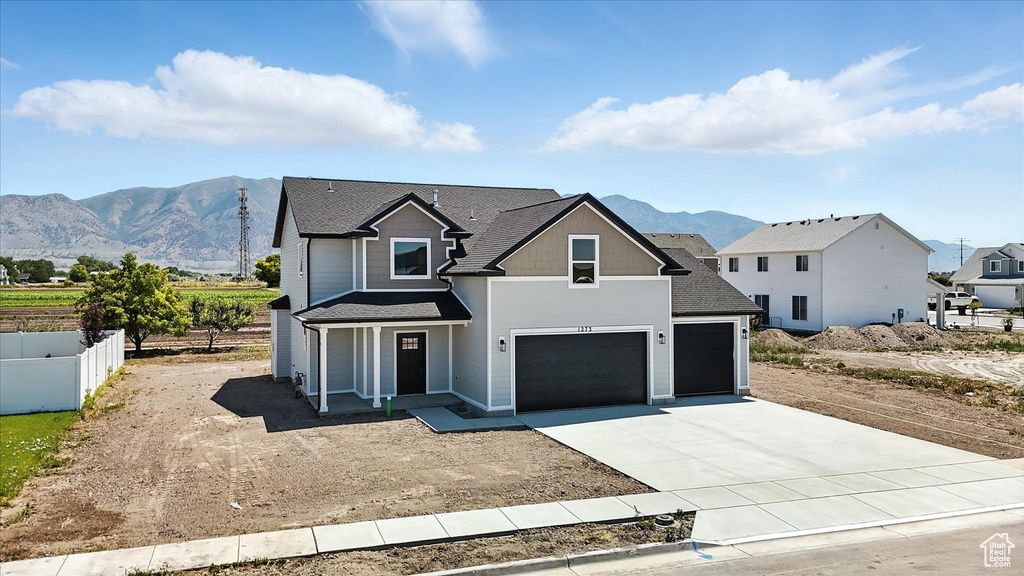 View of front of home with driveway, a mountain view, a shingled roof, a porch, and an attached garage