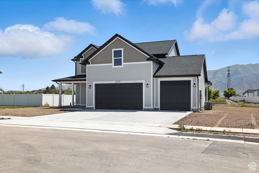 View of front facade with a mountain view, concrete driveway, a shingled roof, and an attached garage