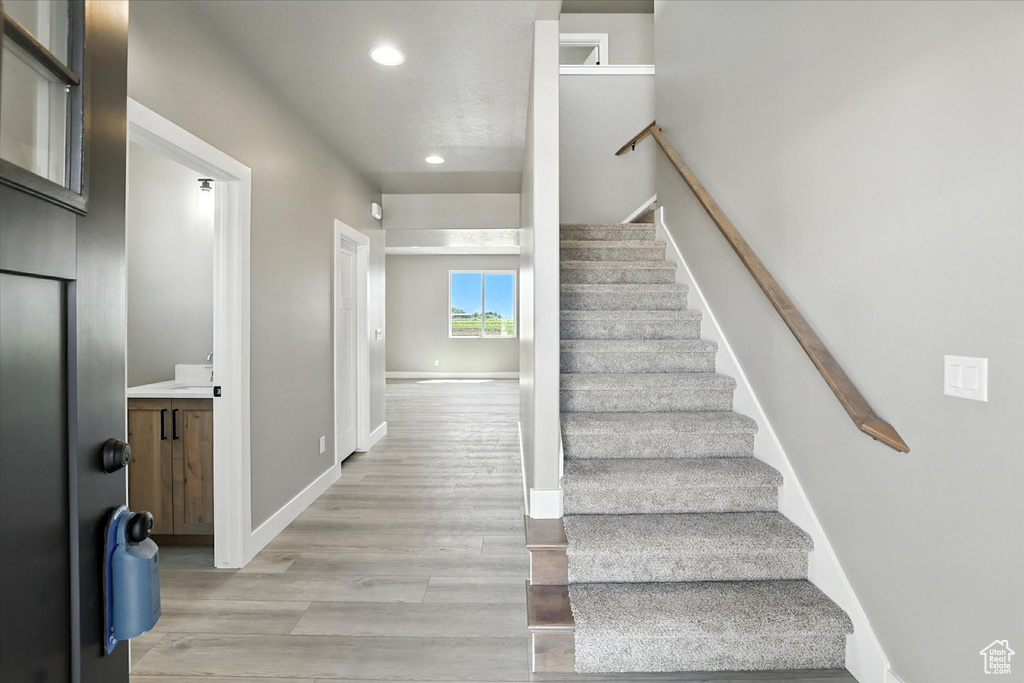 Staircase featuring wood finished floors and recessed lighting