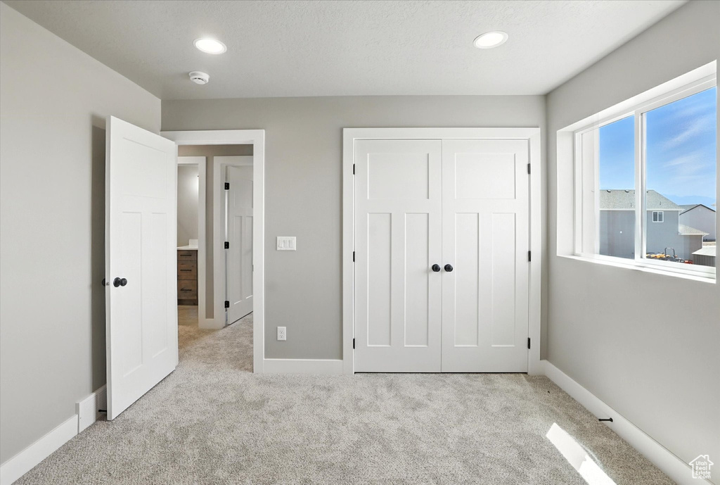 Unfurnished bedroom featuring light colored carpet, a closet, and recessed lighting