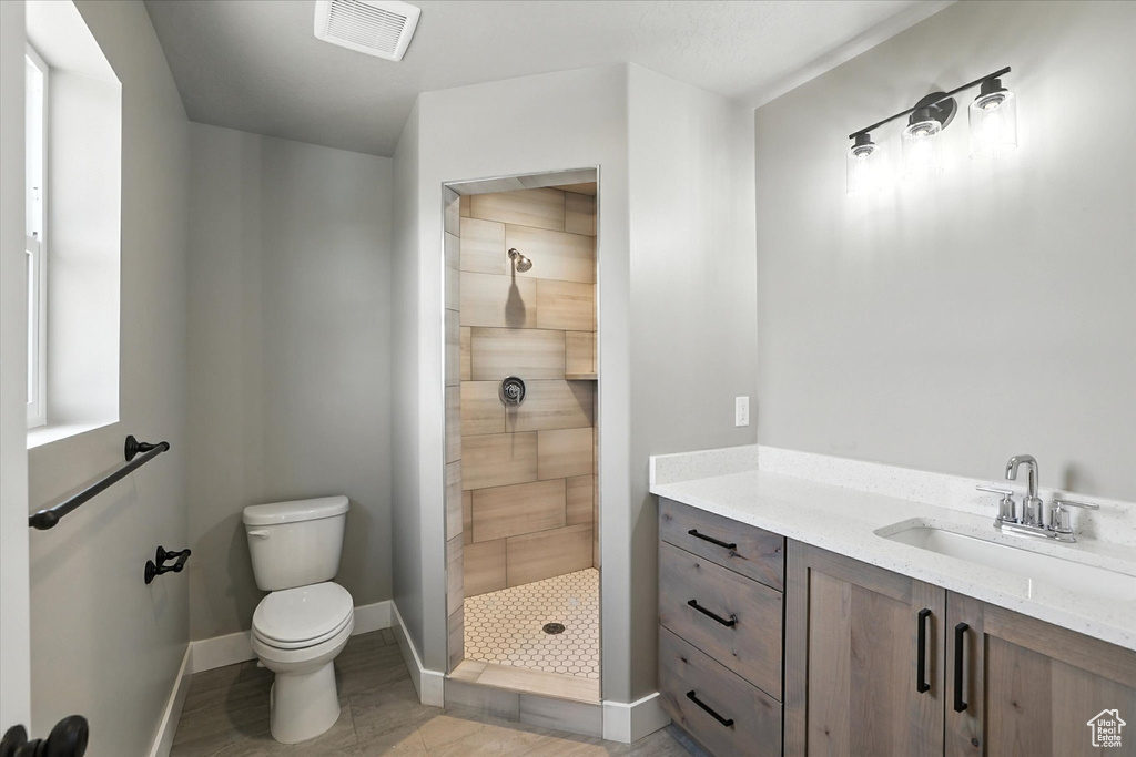 Full bath with tiled shower and vanity