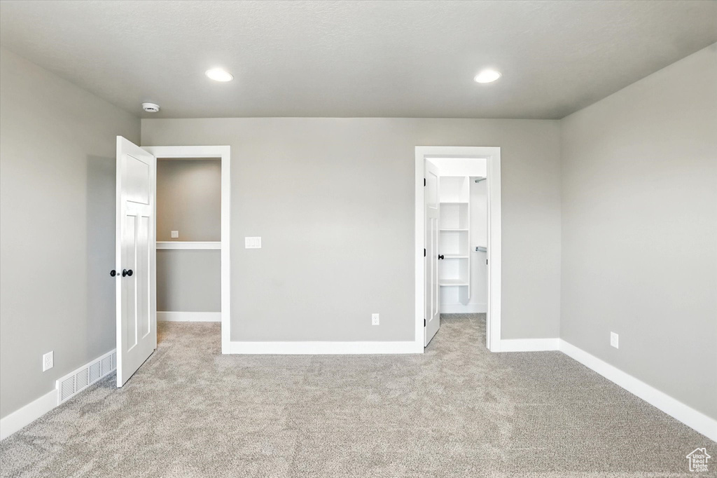 Unfurnished bedroom featuring carpet flooring, a walk in closet, and recessed lighting