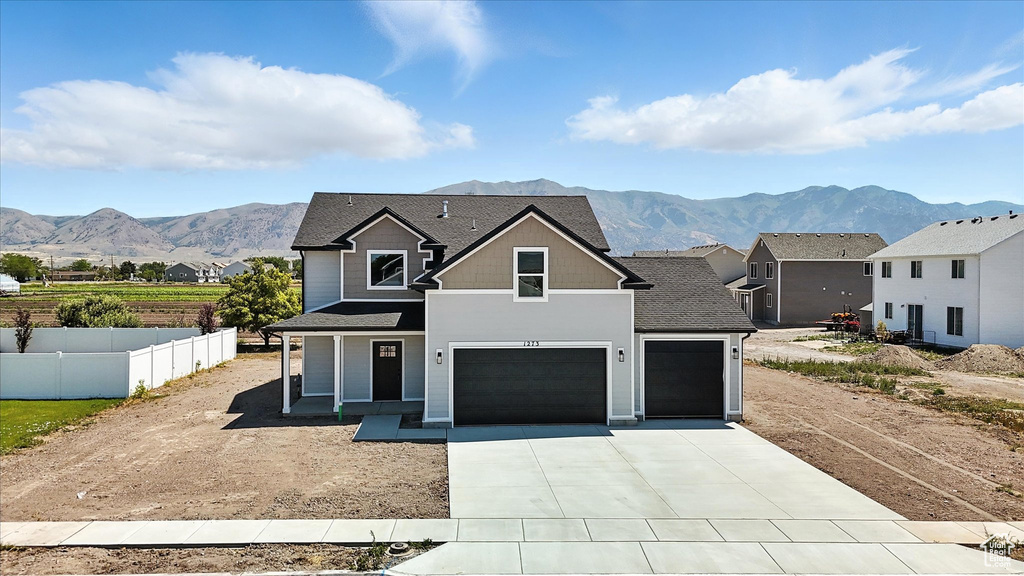 View of front of home featuring a mountain view, concrete driveway, an attached garage, and roof with shingles