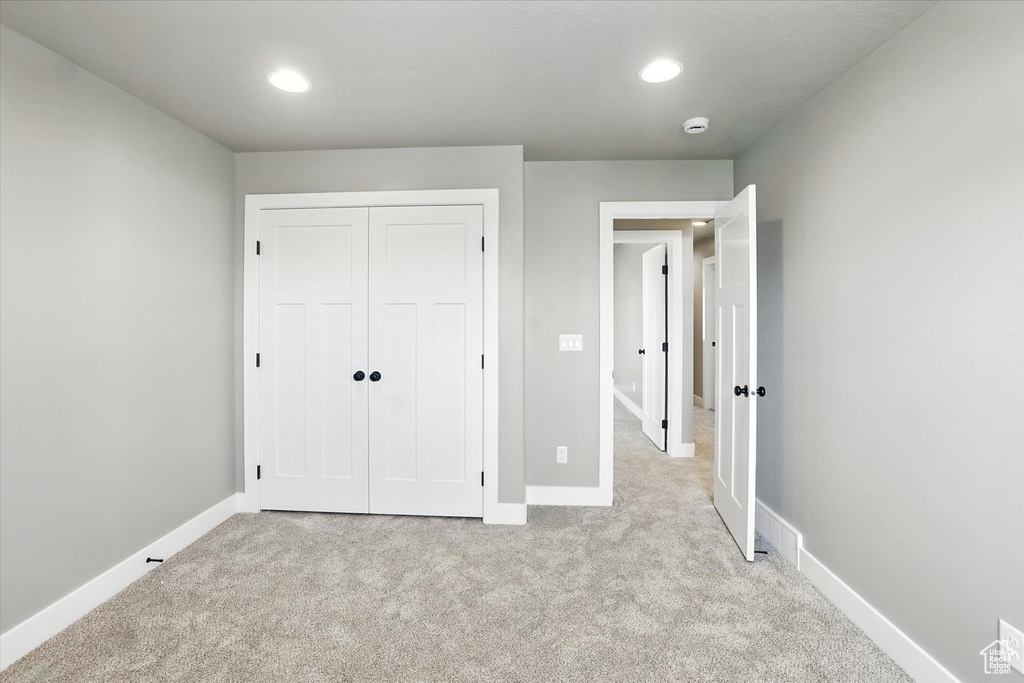 Unfurnished bedroom featuring light carpet, a closet, and recessed lighting