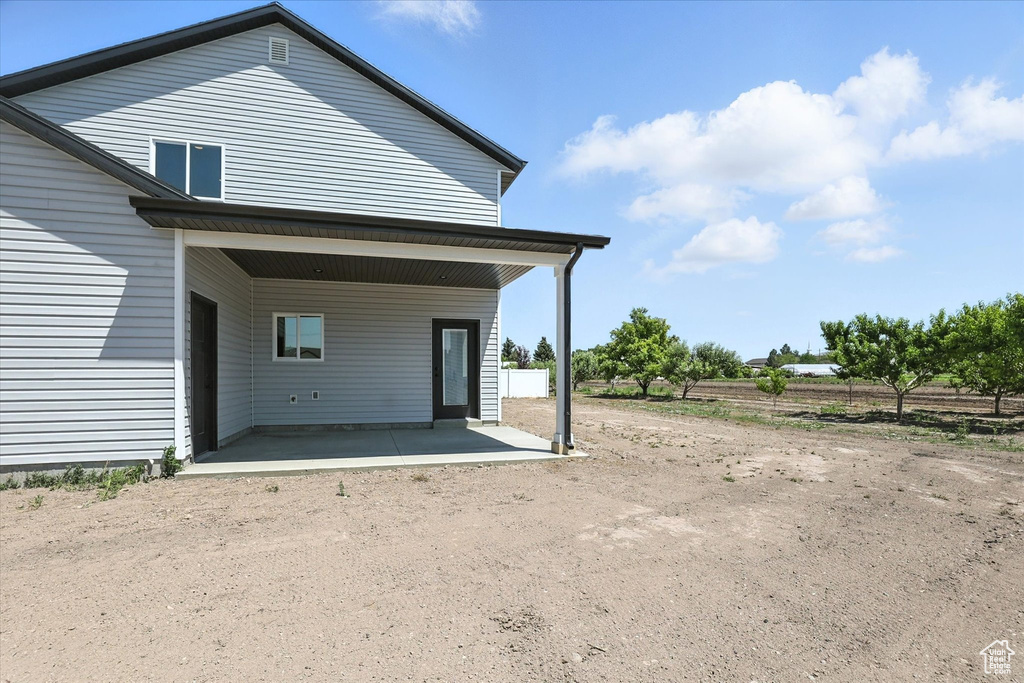 Rear view of house featuring dirt driveway and a patio area