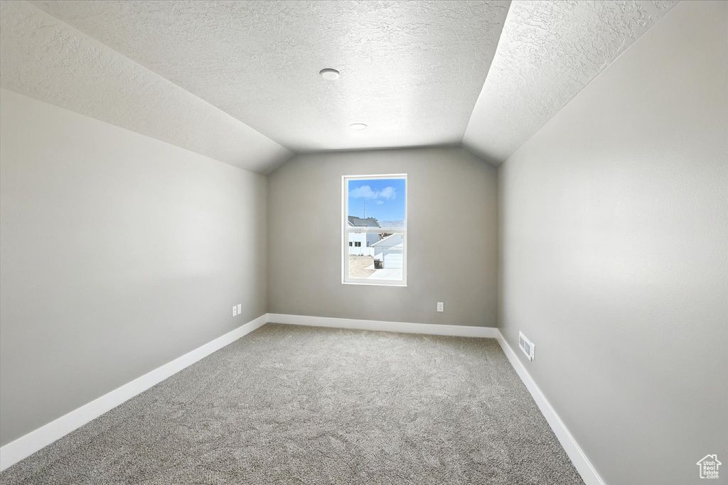 Bonus room featuring carpet flooring, vaulted ceiling, and a textured ceiling