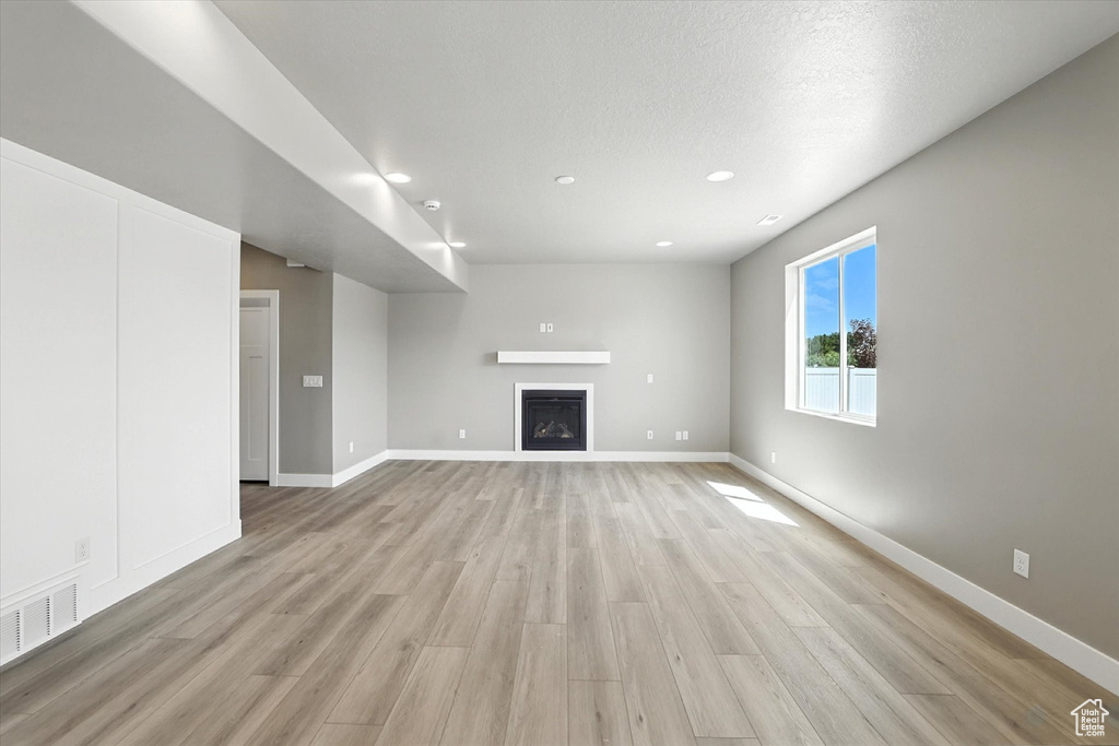Unfurnished living room with light wood-style floors, a fireplace, and recessed lighting