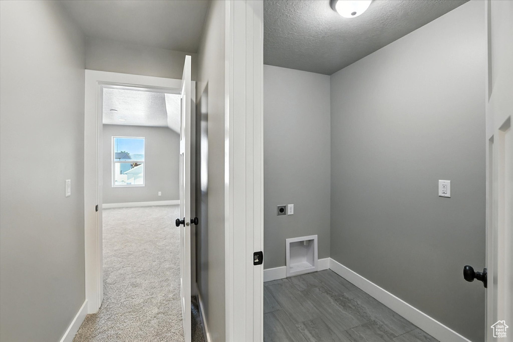 Washroom with electric dryer hookup and a textured ceiling