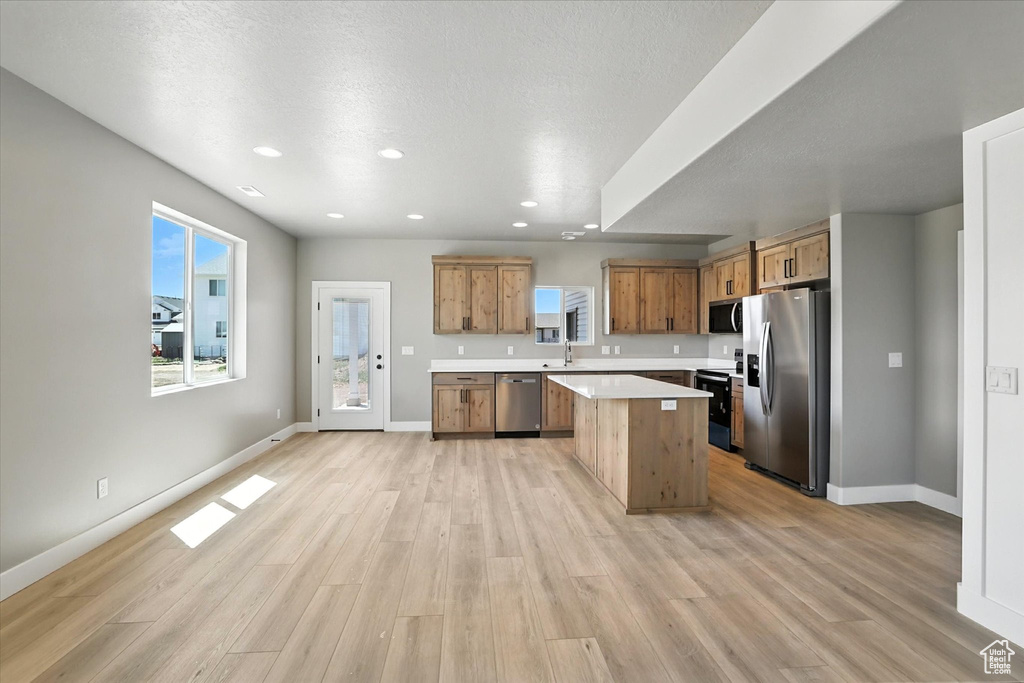Kitchen featuring appliances with stainless steel finishes, light countertops, light wood-style floors, a center island, and recessed lighting