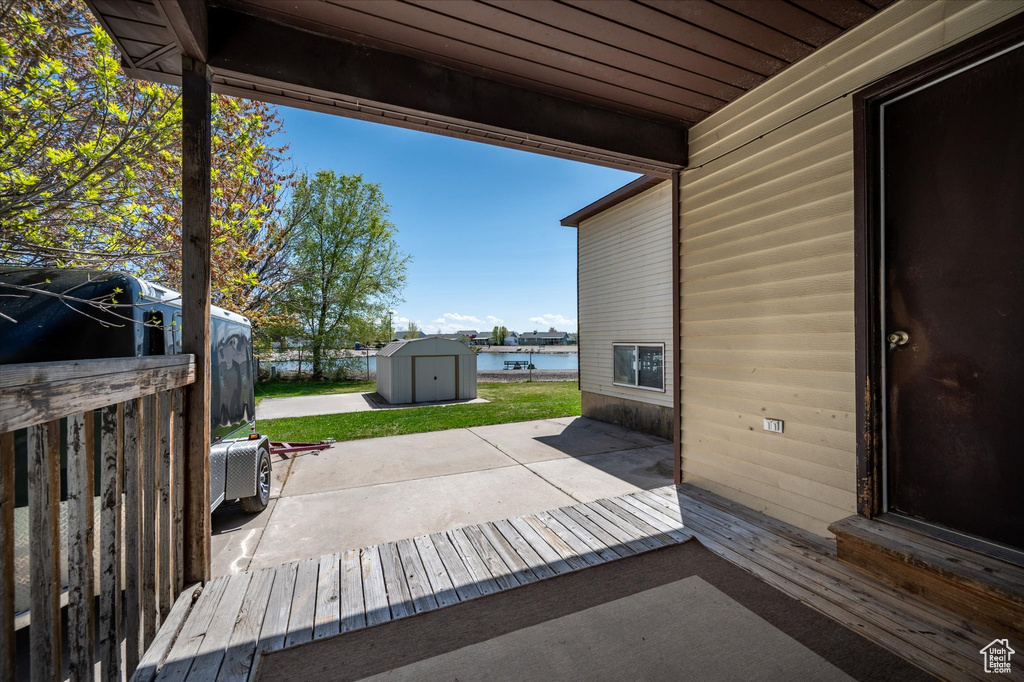 View of patio with an outdoor structure, a water view, and a storage shed