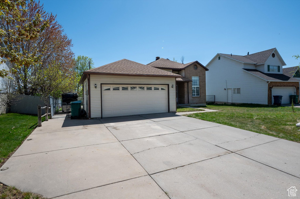 Single story home with a front lawn, fence, driveway, and an attached garage