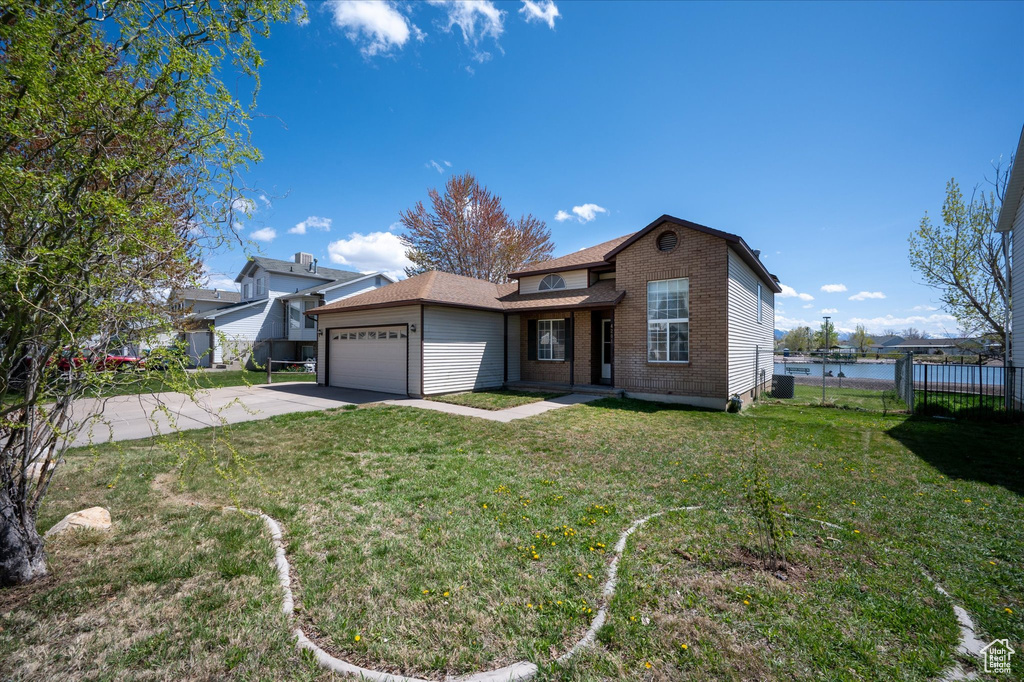 View of front of house with a front lawn, driveway, fence, a garage, and brick siding