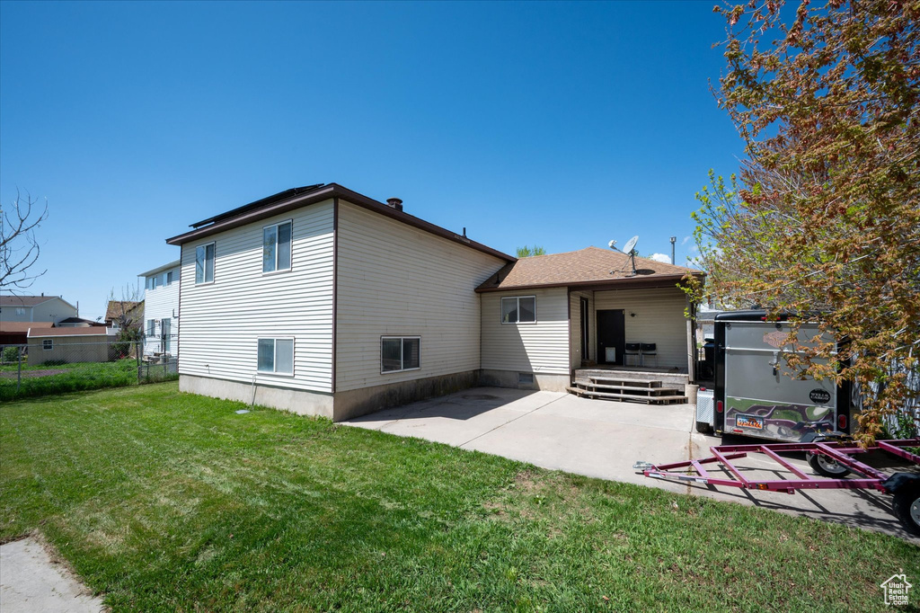 Rear view of property featuring fence, a yard, and a patio