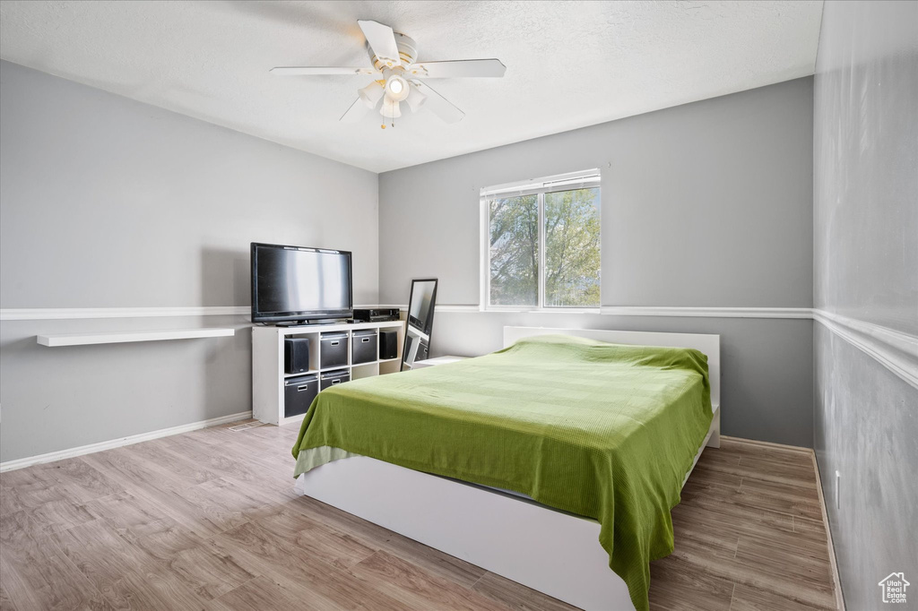 Bedroom with wood finished floors, a ceiling fan, and baseboards
