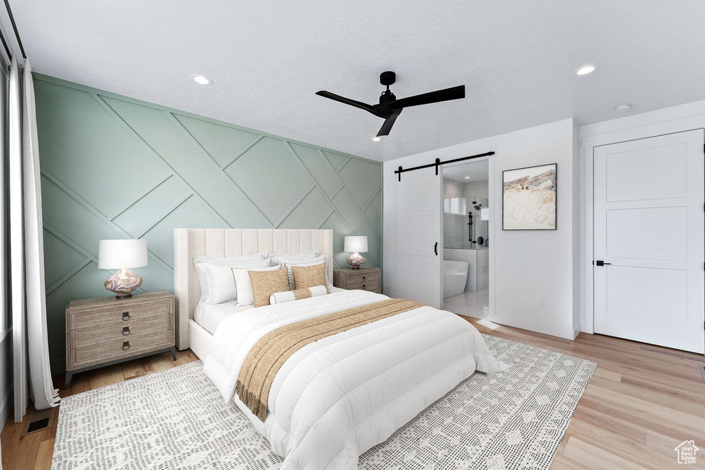 Bedroom with recessed lighting, a barn door, wood finished floors, and a decorative wall