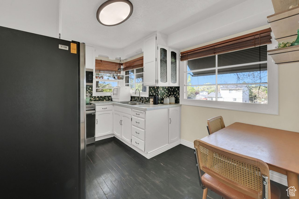 Kitchen featuring light countertops, freestanding refrigerator, a sink, and white cabinetry