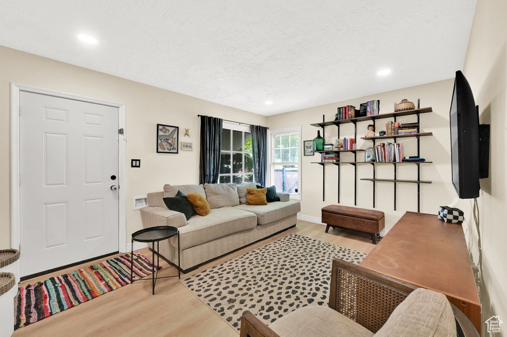 Living room with baseboards, wood finished floors, a textured ceiling, and recessed lighting