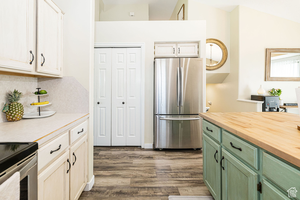Kitchen with backsplash, freestanding refrigerator, green cabinets, wood counters, and dark wood-style flooring