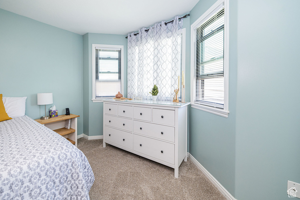Bedroom featuring light carpet, multiple windows, and baseboards
