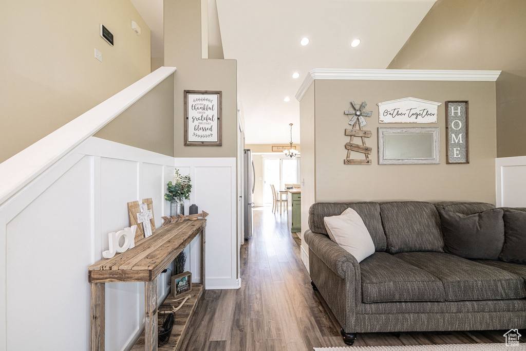 Living area featuring recessed lighting, a decorative wall, dark wood-style flooring, wainscoting, and a notable chandelier