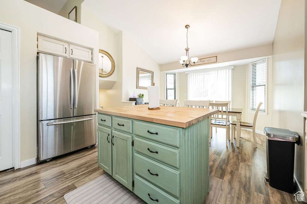 Kitchen featuring dark wood-style floors, vaulted ceiling, freestanding refrigerator, green cabinets, and butcher block counters